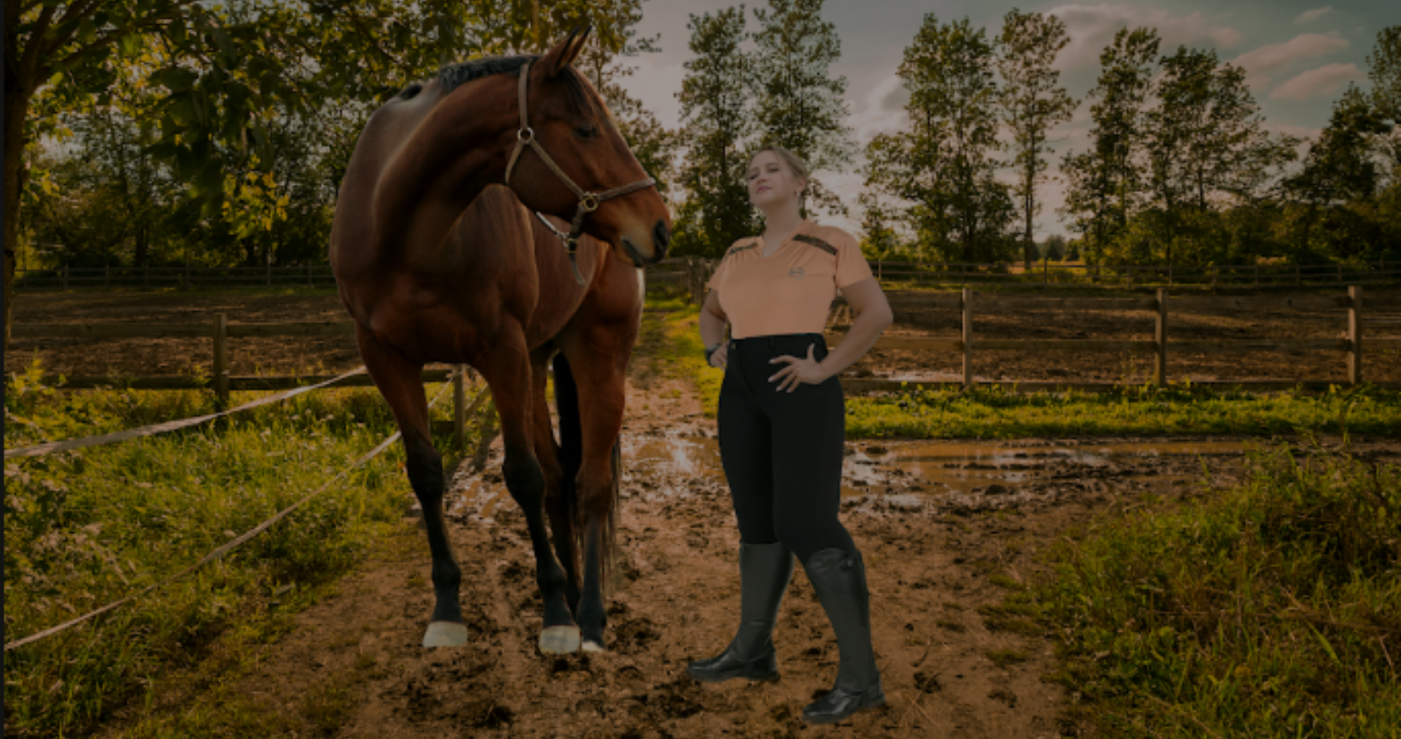 Woman standing next to bay horse in muddy field wearing plus size equestrian clothing and plus size riding breeches