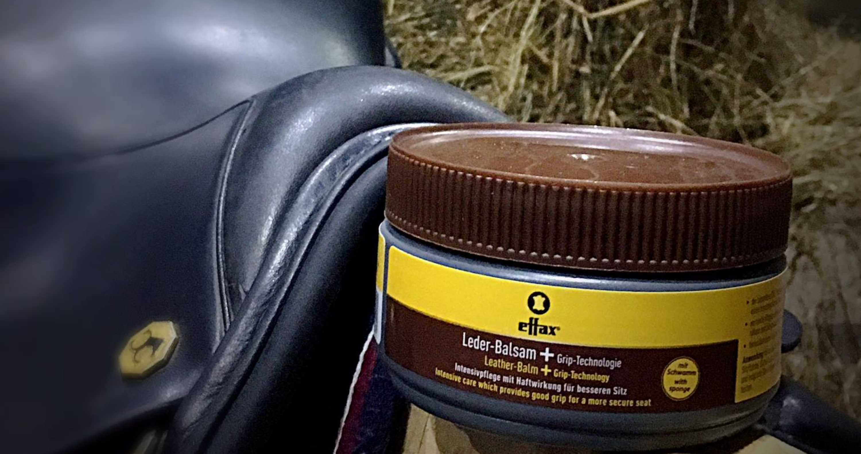 saddle cleaner, saddle conditioner balanced in front of black dressage saddle