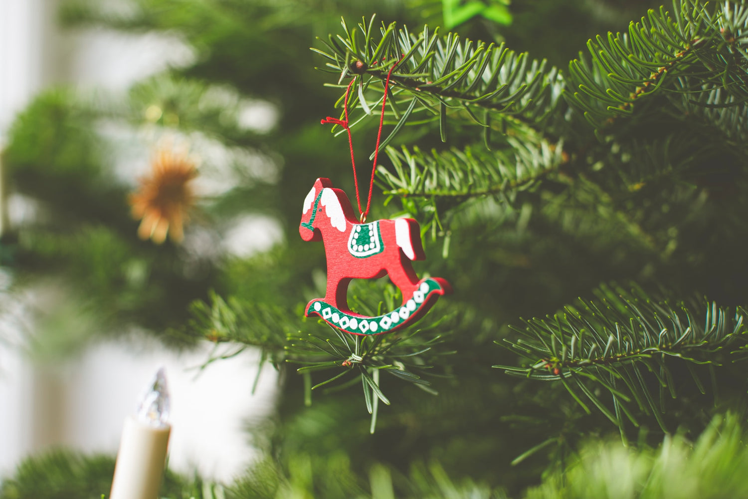 holiday horse gifts for tweens, small red rocking horse tree ornament hangs from pine tree